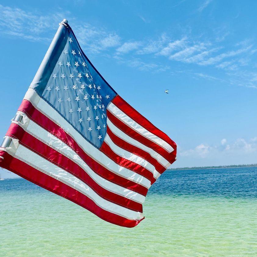 United States flag waving in the wind on the water.